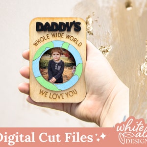 May include: A wooden sign with a photo frame in the shape of a world map. The sign says "Daddy's Whole Wide World We Love You".