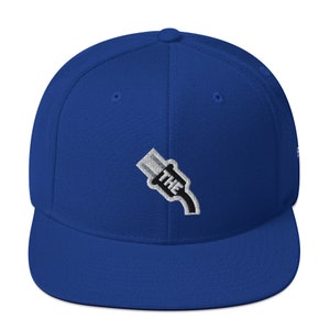 Puede incluir: Una gorra de béisbol azul real con una imagen bordada en blanco y negro de un enchufe con la palabra "THE" en ella.