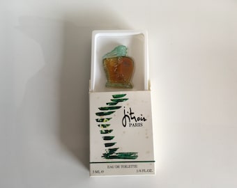 May include: A vintage perfume bottle in a white box. The bottle is a unique shape with a light brown body and a light blue top. The box has the words "jitrois PARIS" and "EAU DE TOILETTE" printed on it.