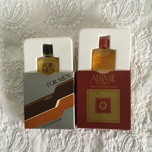 May include: Two small cologne bottles with brown and gold boxes. The box on the left says "For Men" and "Loresté" with the text "Eau de Toilette 90°". The box on the right says "Abime de Loresté" with the text "Parfum de Toilette 85°".
