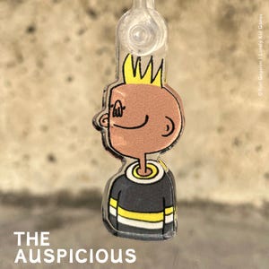 Könnte beinhalten: Eine Comicfigur mit gelbem Haar, die ein schwarz-gelb gestreiftes Hemd trägt. Die Figur lächelt und schaut nach oben. Das Bild ist ein Anhänger oder ein Anhänger.