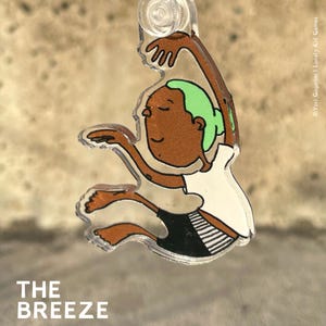 Könnte beinhalten: Ein durchsichtiger Acryl-Schlüsselanhänger mit einer Cartoon-Illustration einer Person mit brauner Haut, grünen Haaren und weißer Kleidung. Die Person springt mit erhobenen Armen in die Luft. Der Text "THE BREEZE" ist unter dem Schlüsselanhänger gedruckt.