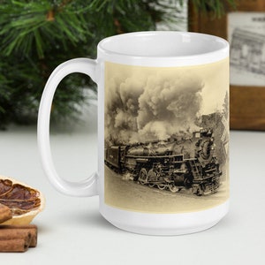 Peut inclure: Une tasse en céramique blanche avec une image en noir et blanc d'une locomotive à vapeur avec de la fumée qui s'échappe du moteur. Le train avance sur une voie ferrée.