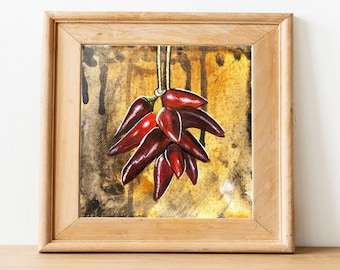 May include: A framed painting of a bunch of red chili peppers hanging from a string against a yellow and brown background.