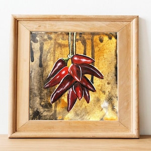 May include: A framed painting of a bunch of red chili peppers hanging from a string against a yellow and brown background.