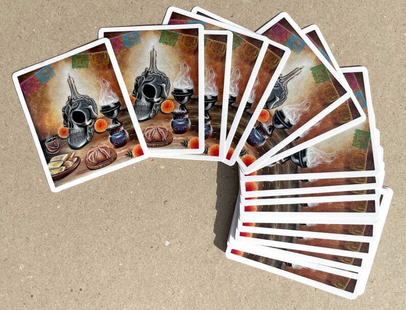 May include: A set of 15 stickers featuring a black and white skull with a candle on top, surrounded by orange fruit, a small cup of coffee, and a traditional Mexican bread. The background is a brown wall with colorful paper streamers.