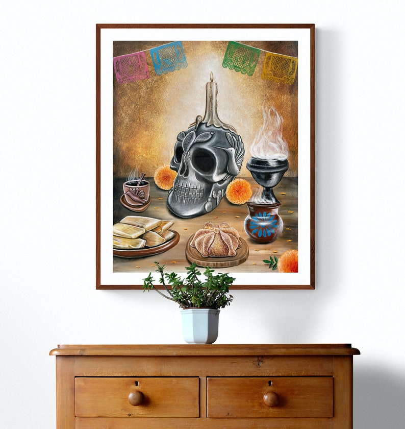 May include: A Day of the Dead altar with a silver skull, a lit candle, a pan de muerto, and a traditional Mexican clay pot with a blue floral design.