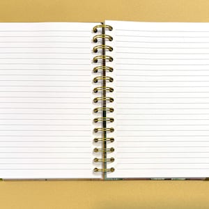 May include: A white spiral bound notebook with lined pages. The notebook is closed and the binding is on the left side.