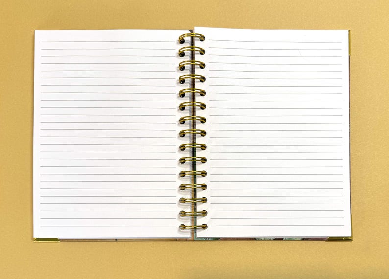 May include: A white spiral bound notebook with lined pages. The notebook is closed and the binding is on the left side.