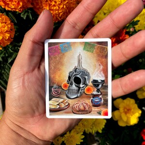 May include: A Day of the Dead altar with a sugar skull, candles, and traditional Mexican food offerings. The altar is decorated with colorful paper flags and flowers.