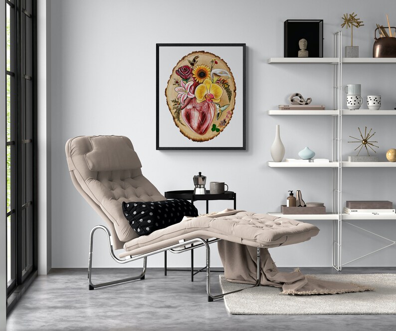 May include: A beige chaise lounge with a black and white polka dot pillow. The chaise lounge is in a living room with a white shelf unit and a framed print of a heart surrounded by flowers on a wood slice.
