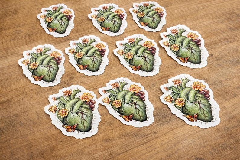 May include: A collection of stickers featuring a detailed illustration of a human heart adorned with flowers and butterflies. The heart is green with intricate veins, and the flowers are yellow and orange.