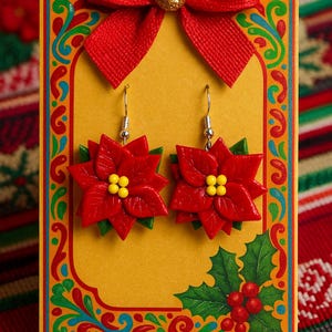 May include: A pair of red poinsettia earrings with yellow centers and green leaves, displayed on a yellow card with a red bow. The card has a decorative border and holly accents, perfect for the holiday season.