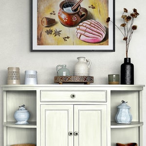 May include: A framed painting of a brown clay mug with a cinnamon stick and steam rising from it, a pink and white pastry, and coffee beans on a wooden surface.