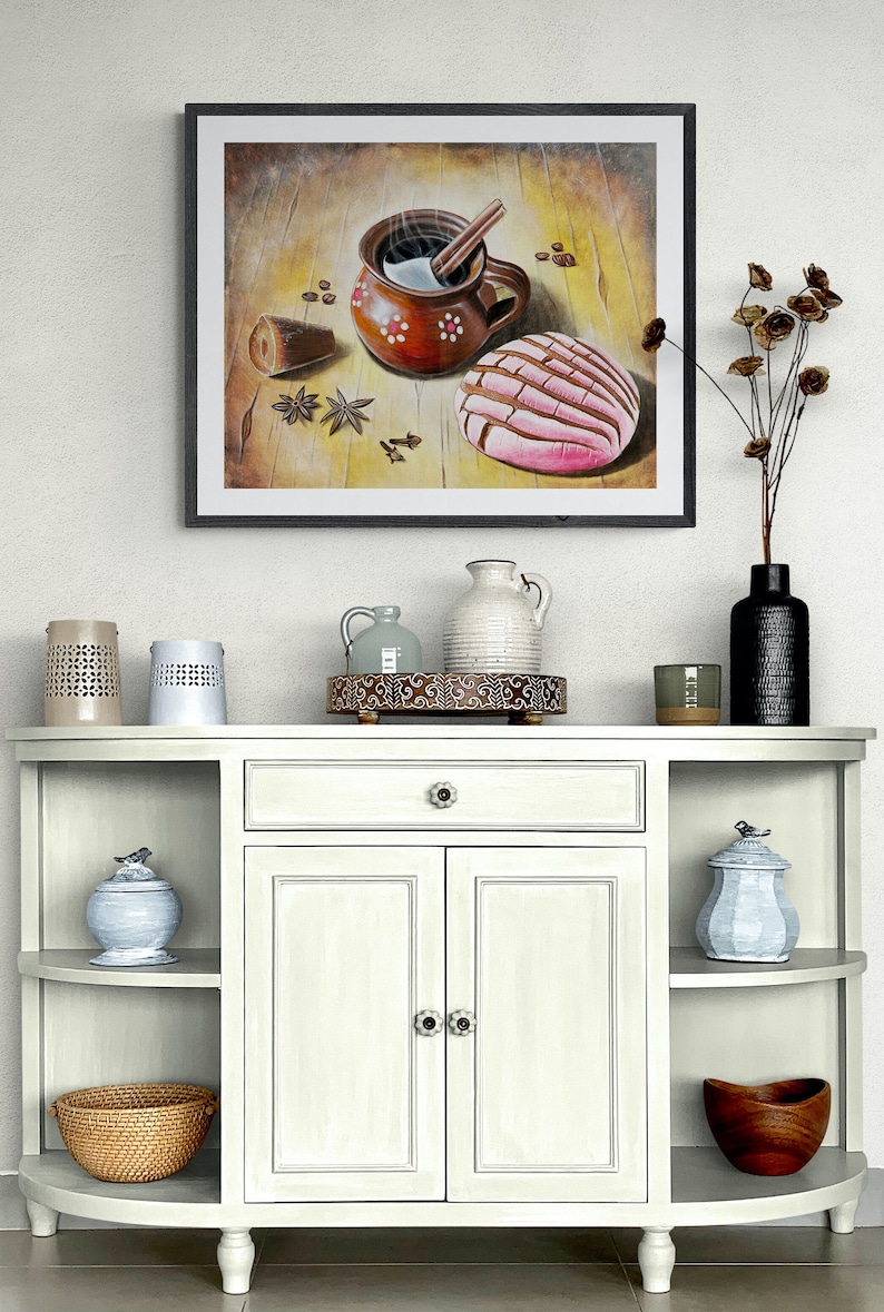 May include: A framed painting of a brown clay mug with a cinnamon stick and steam rising from it, a pink and white pastry, and coffee beans on a wooden surface.
