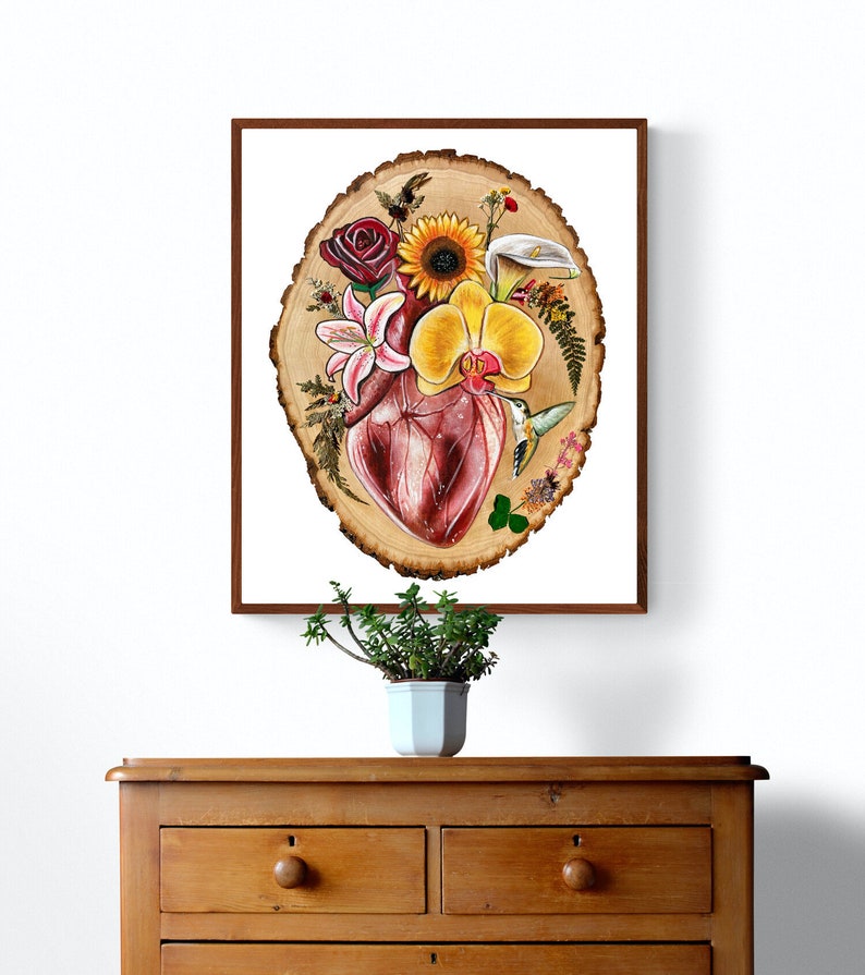 May include: A painting of a human heart surrounded by flowers and a hummingbird on a wood slice background.