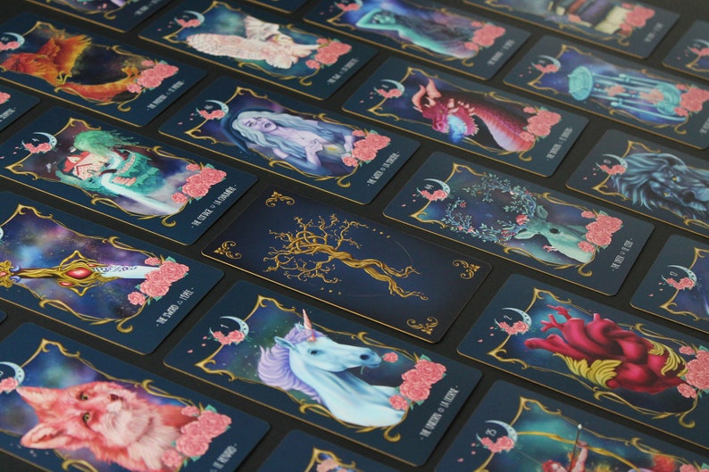 May include: A set of tarot cards with a dark blue background and gold accents. Each card features a different illustration with a celestial theme. The cards are arranged in a grid pattern, with the top row showing the cards in their entirety and the bottom row showing the cards from a closer perspective.