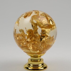 May include: A gold and clear glass sphere knob with a gold metal base. The sphere is filled with gold leaf.