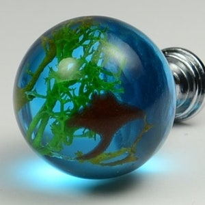 May include: A blue glass globe with green and brown inclusions, mounted on a silver knob. This decorative knob is perfect for adding a unique touch to furniture.
