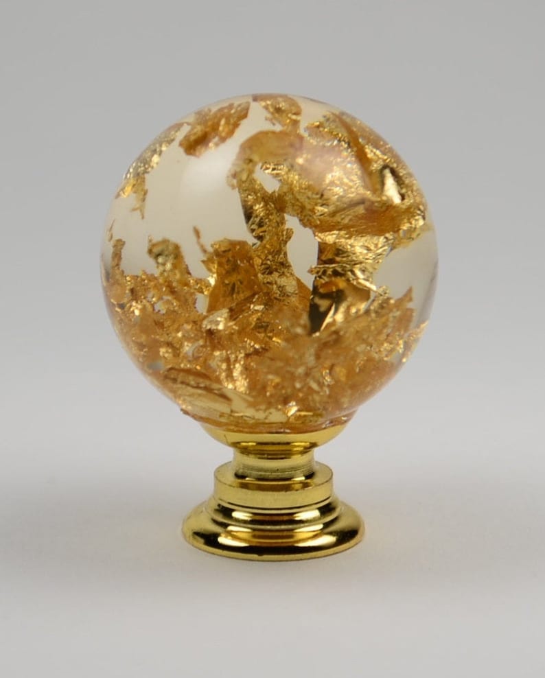May include: A gold and clear glass sphere knob with a gold metal base. The sphere is filled with gold leaf.