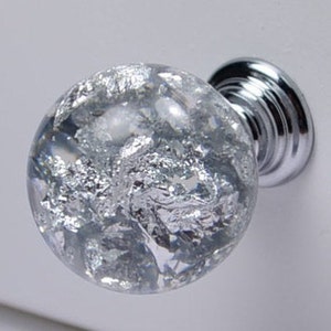 May include: A silver glass cabinet knob with a clear glass sphere and a silver metal base.