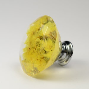 May include: A yellow diamond-shaped cabinet knob with dried flowers encased in clear resin. The knob has a chrome base.