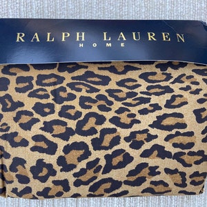 Könnte beinhalten: Gefaltetes Bettwäsche-Set von Ralph Lauren Home mit Leopardenmuster. Die Bettwäsche hat einen beigefarbenen Hintergrund mit dunkelbraunen und schwarzen Flecken. Die Oberseite der Verpackung ist schwarz mit goldfarbenen Buchstaben.