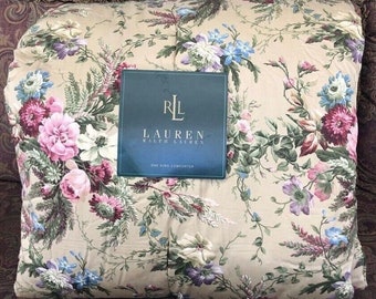 May include: A beige king-size comforter with a floral pattern in shades of pink, purple, blue, and green. The comforter features a design of large flowers and vines. The comforter has a dark blue label with the text "LAUREN RALPH LAUREN".