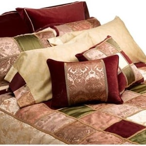 May include: A patchwork quilt set with a variety of colors and patterns, including burgundy, gold, and green. The set includes a quilt, two pillowcases, and several decorative pillows.