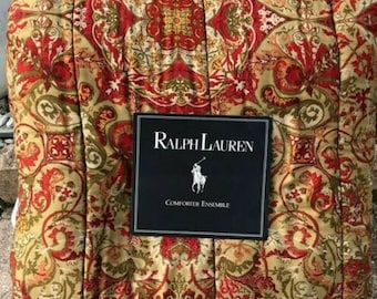 May include: A Ralph Lauren comforter ensemble featuring a detailed floral pattern in red, green, and gold. The comforter has a quilted design and is folded. The Ralph Lauren label is visible.