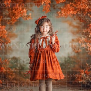 May include: A young girl in an orange dress and bow stands in front of a backdrop of fall foliage. The dress has long sleeves and a white collar with a bow. She holds a few red leaves. The background features a blurred forest scene.