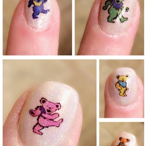 May include: Nail art featuring dancing bear designs in various colors, including blue, green, pink, yellow, and orange. The nail art is applied on a light, shimmery base, showcasing the colorful bears.