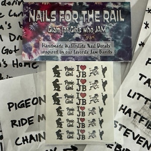 May include: Handmade waterslide nail decals with a variety of designs. The decals are inspired by Jam Bands and feature text that says "Panic Girl I JB". The top of the image has the text "NAILS FOR THE RAIL".