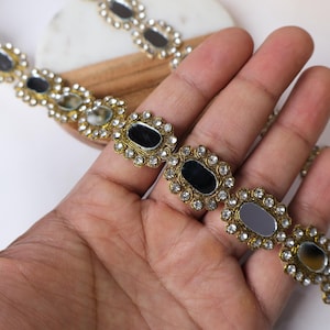 May include: Gold trim embellishment with oval-shaped mirrored pieces and clear rhinestones.