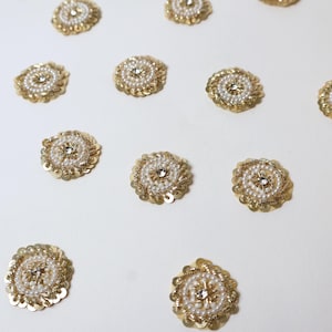 Op de afbeelding: Gouden en witte kralen applicaties met pailletten en imitatieparels. Elke applicatie heeft een centrale strass-steen omgeven door witte kralen en een gouden paillettenrand. Ideaal voor knutselprojecten.