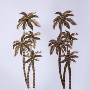 May include: Two sets of sequined palm tree appliques. The trees have brown trunks and gold and bronze-coloured leaves. The appliques are on a white background. Each set has three palm trees.