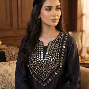 Puede incluir: Top negro de manga larga con intrincados adornos de espejo alrededor del escote. El top forma parte de un conjunto a juego, con un diseño detallado en la manga. Un conjunto de ropa formal.