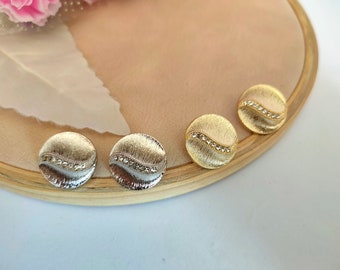 May include: Three round gold-toned earrings with a wavy design and clear rhinestones.