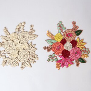 Könnte beinhalten: Zwei gestickte Blumenpatches, einer in Creme und einer in Rosa, Rot, Orange und Gelb.