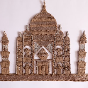 Puede incluir: Una aplicación bordada en oro del Taj Mahal, un famoso monumento indio. La aplicación está hecha de hilo de oro y cuentas y es perfecta para agregar un toque de elegancia a cualquier proyecto.