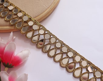 May include: Gold trim with teardrop-shaped mirrored embellishments. This trim is perfect for adding a touch of sparkle to any project.