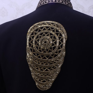 May include: A navy blue jacket with an elaborate gold-colored beaded design on the back. The design is a series of concentric circles and geometric shapes. The jacket has a detailed collar.