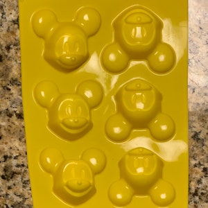Può includere: Stampo in silicone giallo con sei cavità a forma di Topolino. Lo stampo è progettato per fare piccoli dolci o dolcetti.