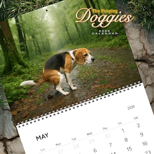 Op de afbeelding: Een kalender voor 2026 met de titel "The Pooping Doggies". De afbeelding toont een beagle hond in een bos. De maand mei is zichtbaar. De hond is bruin, zwart en wit. De kalender heeft een spiraalbinding bovenaan.