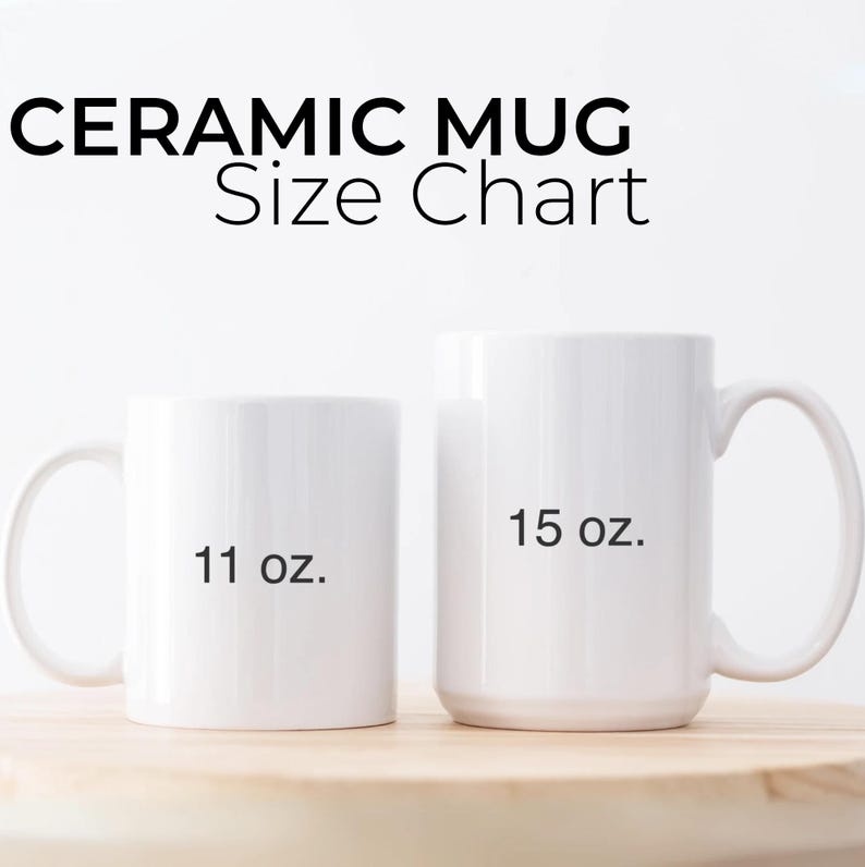 May include: Two white ceramic mugs, one labeled "11 oz." and the other "15 oz." The text "CERAMIC MUG Size Chart" is above the mugs. The mugs are on a light brown wooden surface.