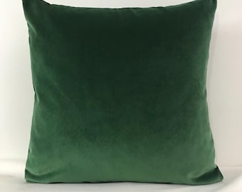 May include: A deep green velvet pillow with a soft, plush texture. The pillow is square and has a simple, elegant design.