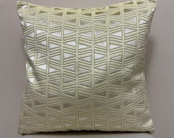 May include: A cream-colored throw pillow with a geometric pattern of embossed triangles.