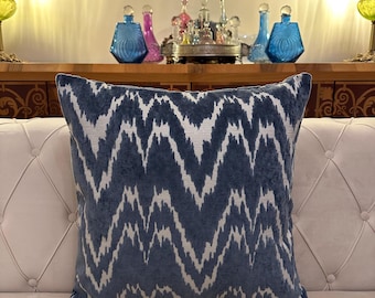 May include: A blue and white patterned throw pillow with a chevron design. The pillow is on a white couch.