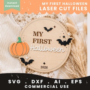 Op de afbeelding: Een rond houten bord met de tekst MY FIRST Halloween en het jaartal 2026. Het ontwerp bevat een gelaagde oranje pompoen, drie zwarte vleermuizen en kleine witte steraccenten. Het bord heeft een dunne gegraveerde randlijn.