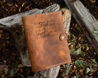 May include: A brown leather journal with a flap closure and a brass snap. The cover is embossed with the words "love, joy, peace, patience, kindness, goodness, faith, gentleness, self-control" and "Fruit of the Spirit."